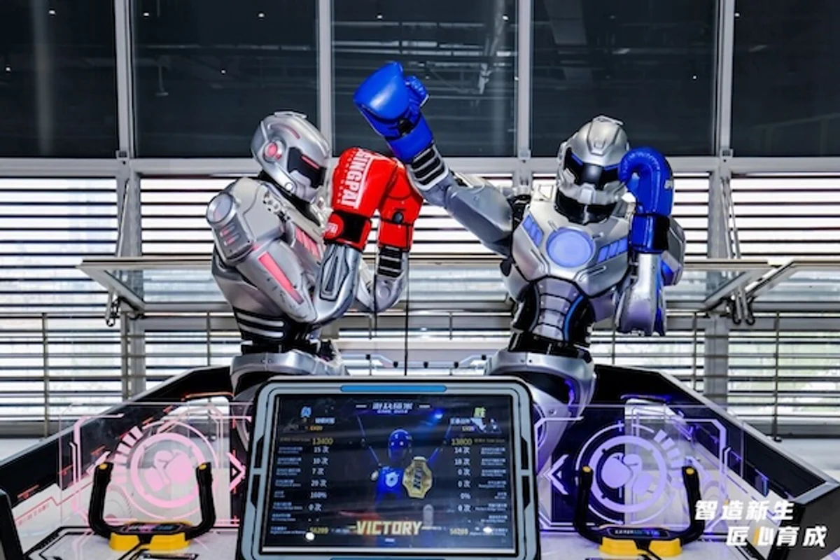Two humanoid boxing robots facing off over a scoreboard reading VICTORY, at a Chinese robotics exhibition