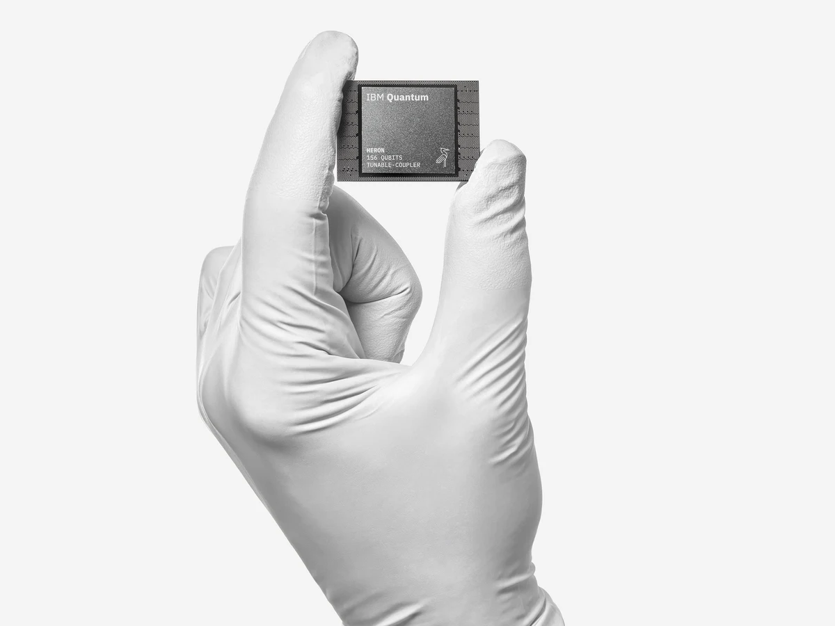 An IBM Quantum Heron processor held in a hand, showing the packaged quantum hardware used in this research programme.