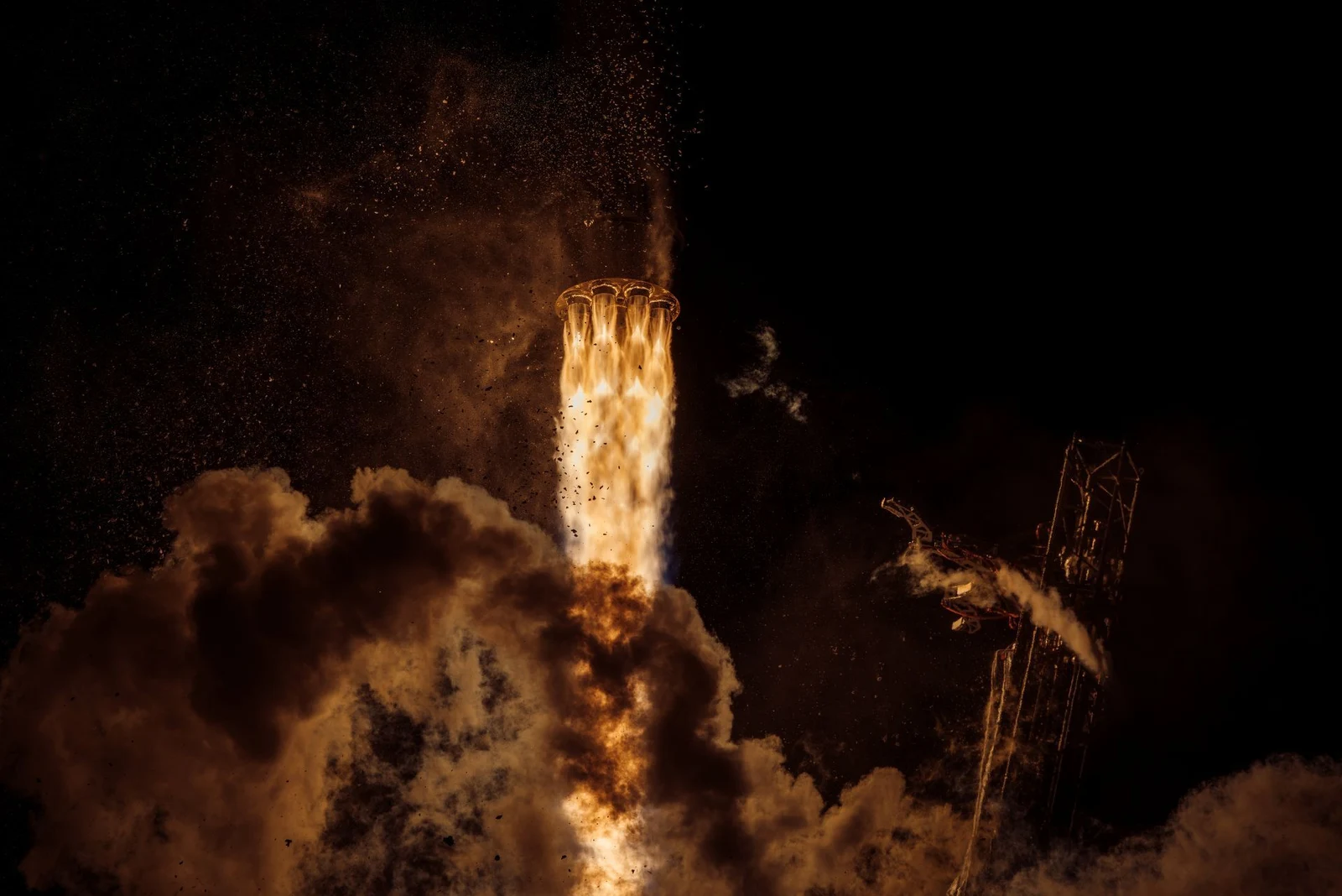 Spectrum lifts off at night, surrounded by illuminated exhaust.