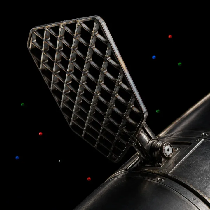 Concept artwork of a titanium grid fin on a booster interstage, drawn as a diagonal waffle lattice with red, blue and green cubes drifting past.