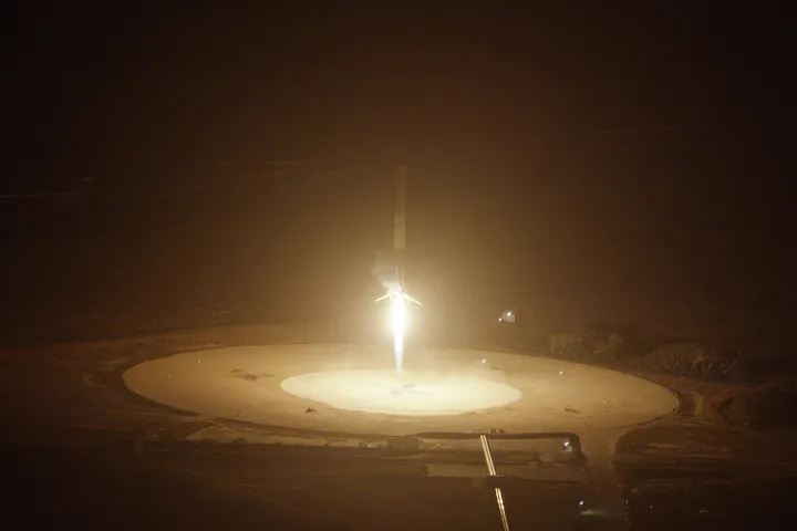Falcon 9 first stage descending towards Landing Zone 1 at night